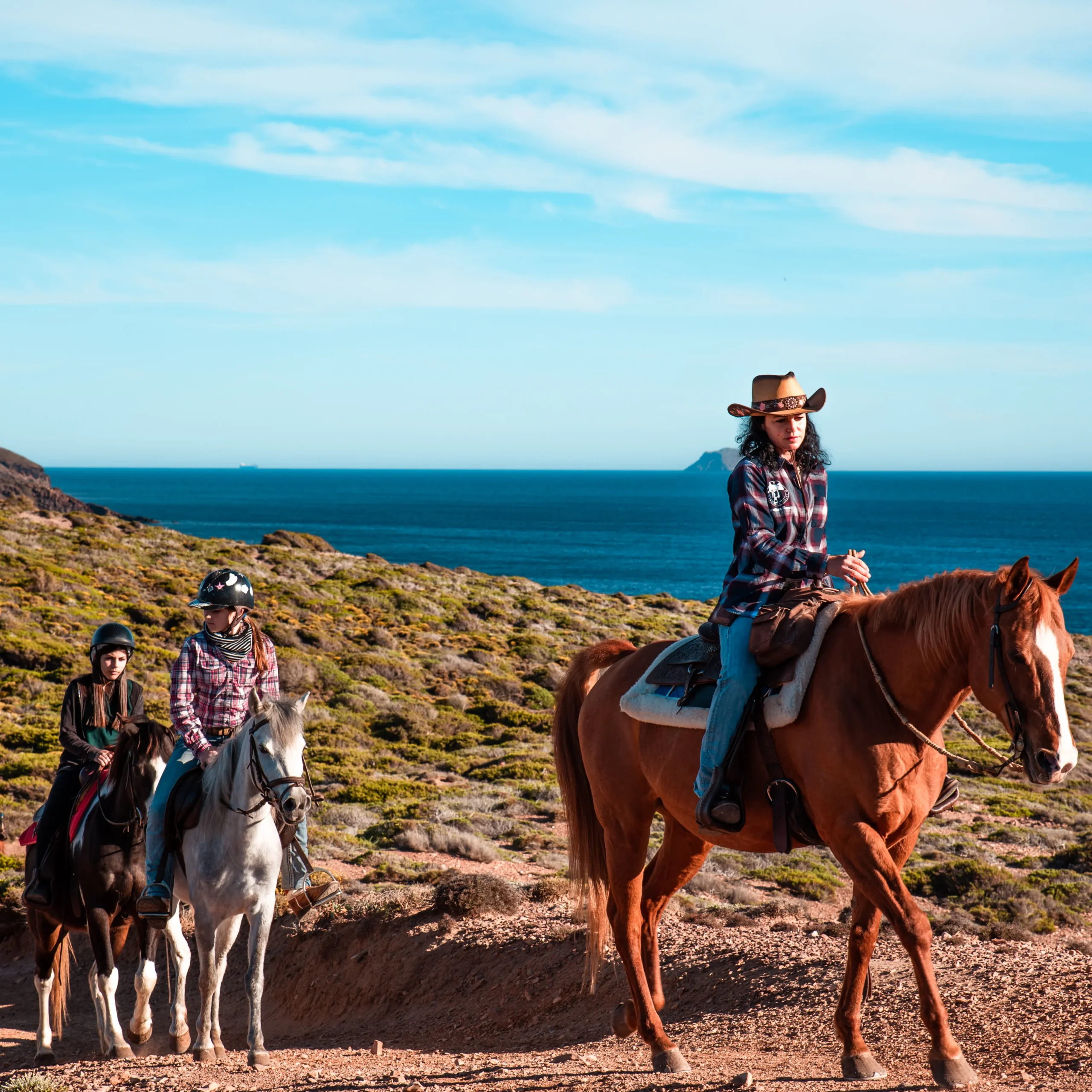 Guide der Carolina Ranch begleitet eine kleine Gruppe von Reitanfängern an der Küste Sardiniens