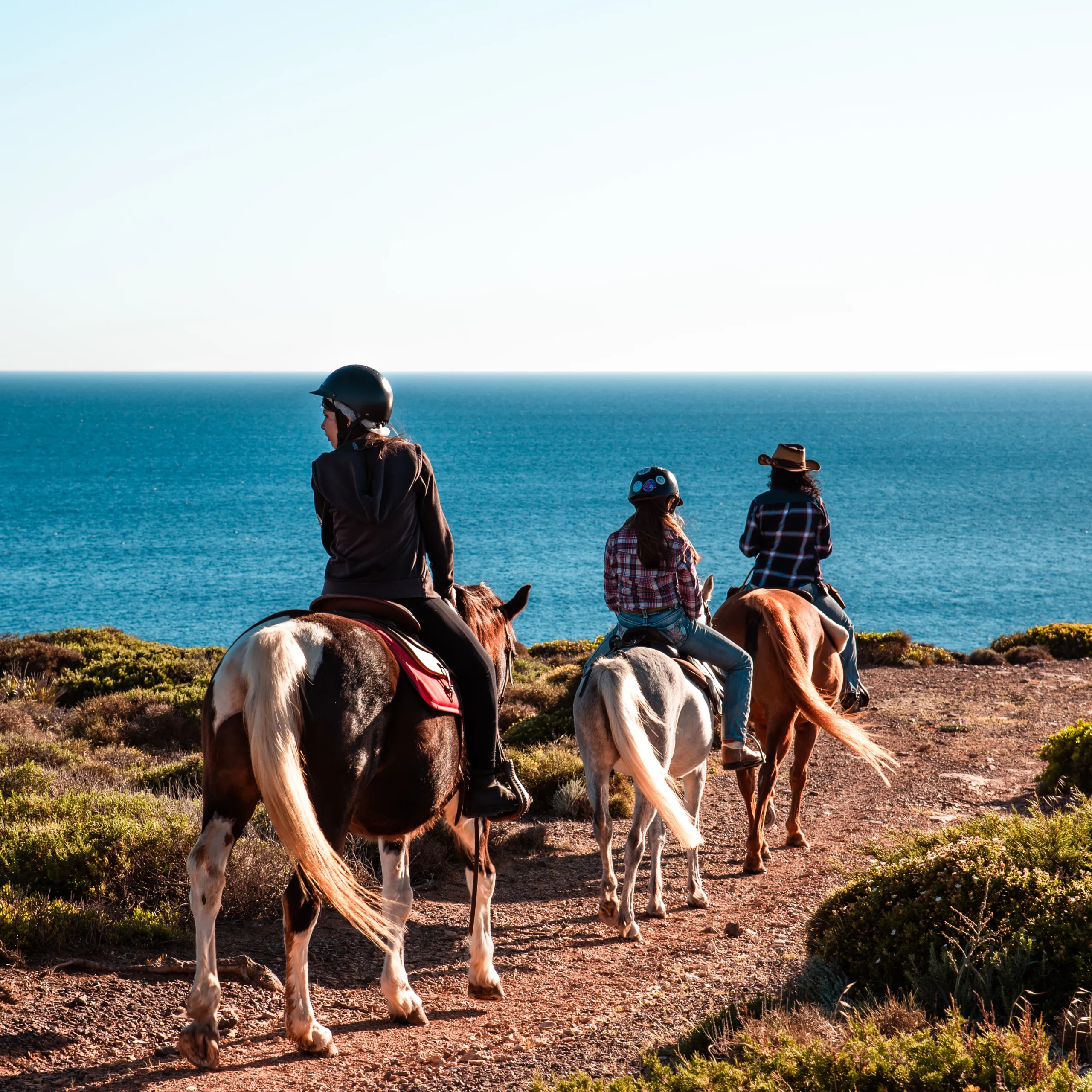 Reiter im Westernsattel auf dem Küstenpfad von Sant'Antioco, Sardinien, mit Blick aufs Meer